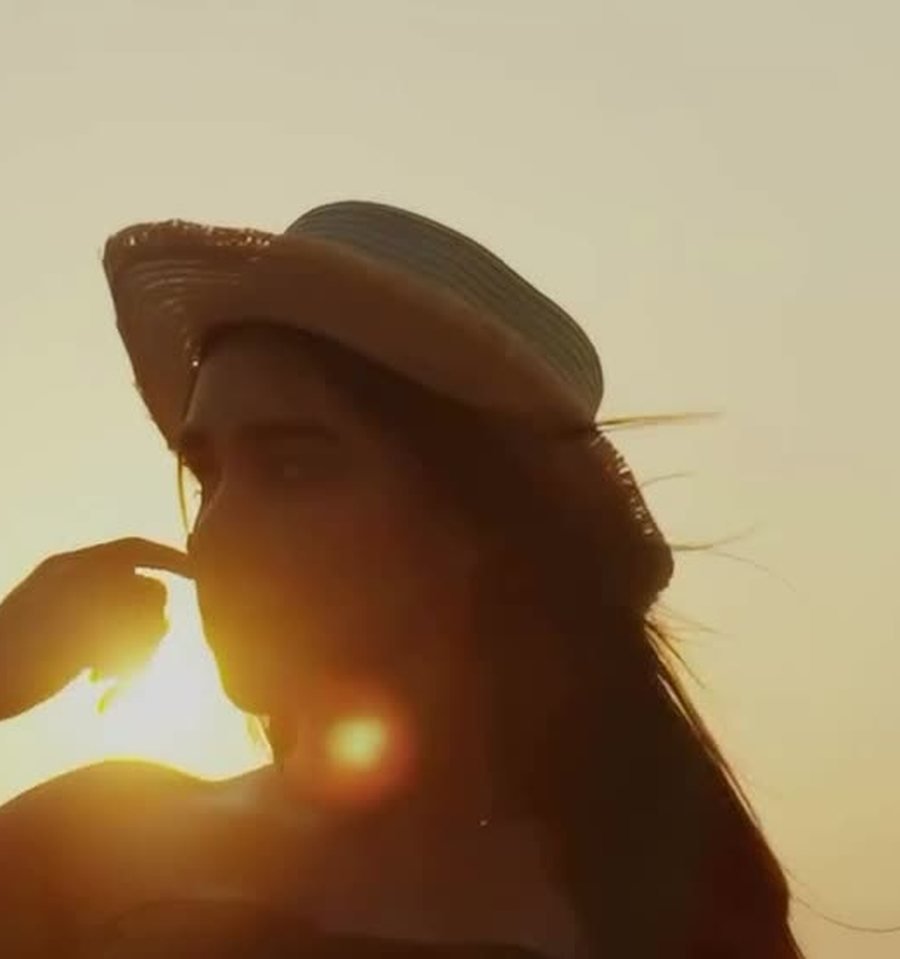 A guest in a straw hat silhouetted against the setting sun